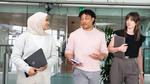 Three individuals walking and conversing in a modern office space. 