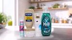 A variety of Unilever's Power Brands arranged on a kitchen counter. From left to right, you can see a jar of Knorr chicken bouillon, a Degree deodorant spray labelled "WHOLE BODY DEO", a box of Magnum ice cream labelled "UTOPIA", a bottle of Dove body lotion pro-ceramides serum, a jar of Dove Intensive Repair cream and a bottle of Persil Wonder Wash. In the background, there's a modern kitchen with plants and various items on the shelves.